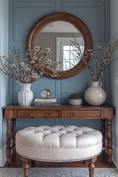 a table with a mirror, vases and flowers on top of it in front of a bench