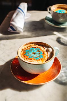 there is a cup of coffee on top of the saucer and another one in the background