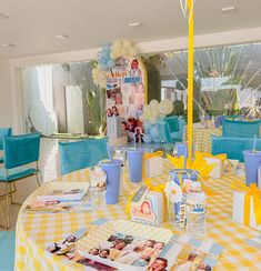 a yellow and white table cloth with pictures on it is set up for a baby's first birthday party