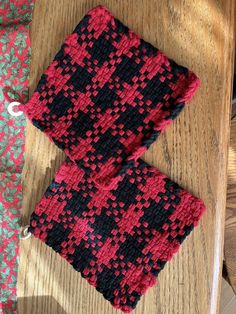 two pieces of knitted cloth sitting on top of a wooden table