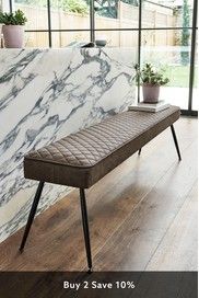 a bench sitting on top of a hard wood floor next to a white marble wall