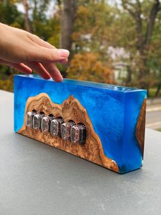 a hand reaching for an object made out of wood and magnets on top of a table