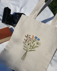 a white tote bag sitting on top of a table next to an open book