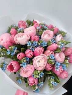 a bouquet of pink roses and blue flowers