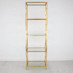 a tall gold shelf with glass shelves on each side, against a plain white wall