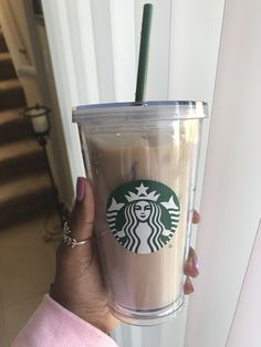 a woman holding up a starbucks cup with a straw in it