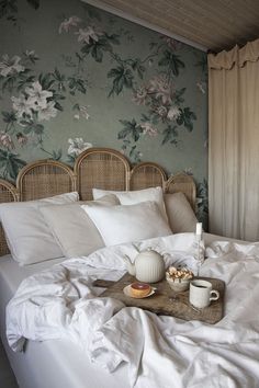 an unmade bed with white linens and two cups of coffee on the tray