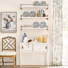 a white table topped with plates and drinks next to a wall mounted shelf filled with dishes