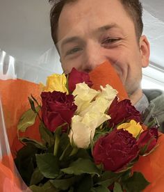 a man is holding flowers and smiling for the camera