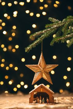 a christmas ornament hanging from the top of a tree with lights in the background