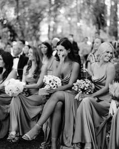 a group of women sitting next to each other in front of a crowd at a wedding