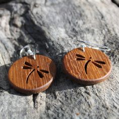 two wooden earrings with dragonflies carved on them