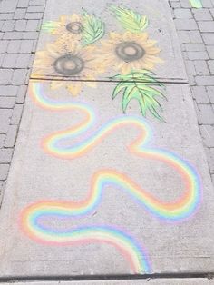 the sidewalk has been painted with sunflowers and rainbow lines on it, as well as flowers