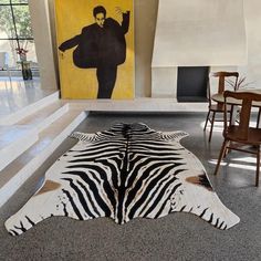 a zebra print rug in the middle of a room with chairs and a painting on the wall