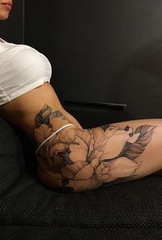 a woman sitting on top of a couch next to a black and white flower tattoo