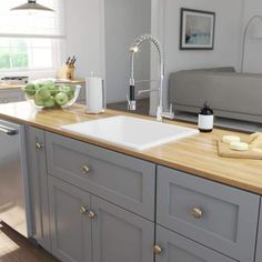 a kitchen with gray cabinets and wooden counter tops is shown in this image, there are green apples on the counter