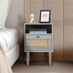 a nightstand with books on it next to a bed