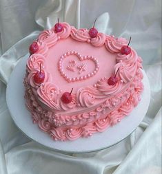 a heart shaped cake with pink frosting and cherries