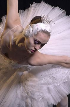 a ballerina in white tutu and tiara with her arms stretched out to the side