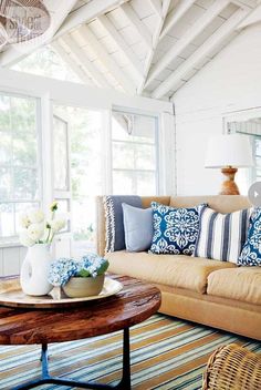 a living room filled with furniture and pillows on top of a wooden table in front of a window