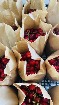 several paper bags filled with cherries on top of a metal rack