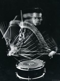 black and white photograph of a man playing the drums in front of an abstract background