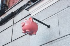 a pink pig hanging from the side of a building