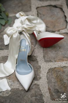 a pair of white high heeled shoes sitting on top of a cobblestone floor