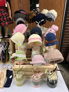 several knitted hats are on display in front of a doll and other items for sale