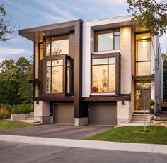 a two story house with large windows and lots of grass