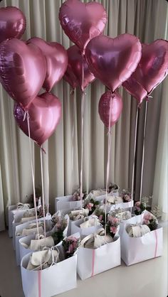 many pink heart shaped balloons are in the shape of bags with flowers and ribbons on them