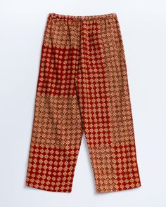 an orange and red patterned pants with buttons on the side, sitting on a white surface