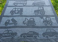 a crocheted blanket with cars and trucks on it sitting in the green grass