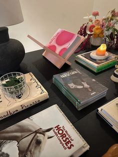 a table topped with lots of books and vases filled with flowers on top of it