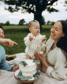 a woman holding a baby and pointing at a cake