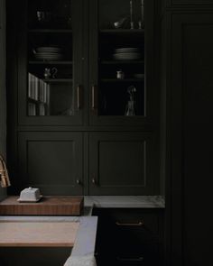 a kitchen with dark green cabinets and white counter tops