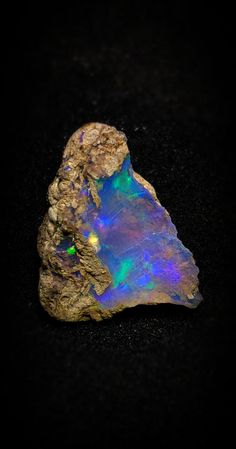 an opalite rock sitting on top of a black surface with a green light in the middle