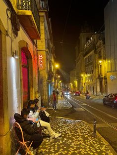 two people sitting on a bench in the middle of an alleyway at night time