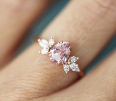 a woman's hand with a pink diamond ring on it