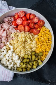 pasta salad with tomatoes, corn, and other vegetables in a white bowl on a table