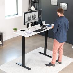 a man standing in front of a desk with a computer monitor and keyboard on it