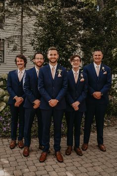 a group of men standing next to each other in front of a house and trees