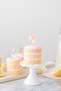 there is a cake with pink icing and lemons on the table next to it