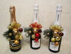 three wine bottles decorated with christmas ornaments and decorations, one is empty the other has two champagne bottles in it