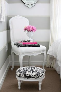 a white chair sitting next to a bed with pink flowers on top of it and a chandelier hanging from the ceiling