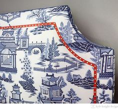 a blue and white bed with red trim on it's headboard is next to a gray wall