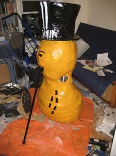 a yellow statue with a black top hat on it's head