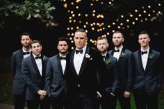 a group of men standing next to each other wearing tuxedos and bow ties