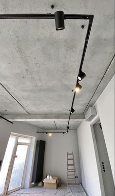 an empty room with some lights on the ceiling and a ladder in front of it