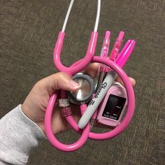 a person holding a pink stethoscope and other medical items in their hand